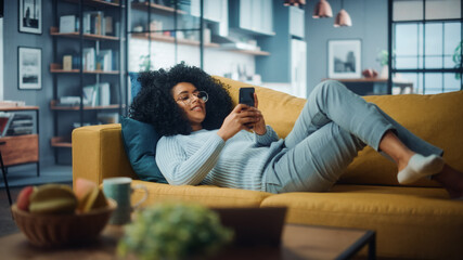 Happy Beautiful Latina Female Using Smartphone in Cozy Living Room at Home. Female Resting on...