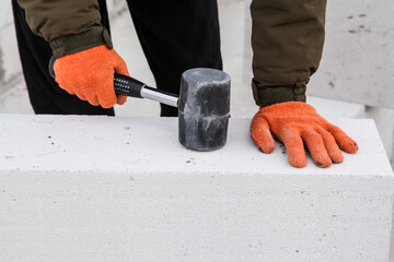 Construction worker beating aerated concrete block with Rubber Hammer. Building manual work