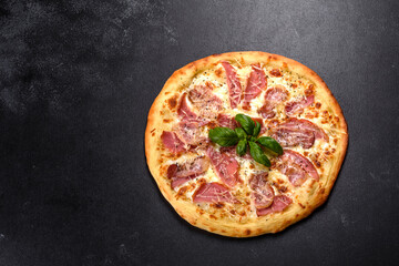 Delicious fresh crispy pizza from the oven with ham, cheese and basil