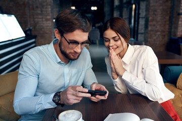 man and woman sitting at the table near the phone communication of work colleagues