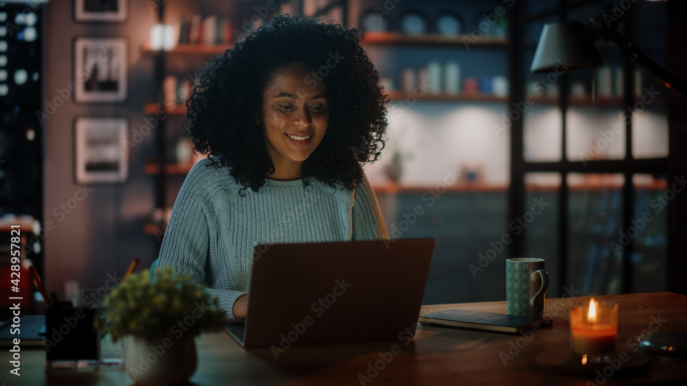 Poster beautiful authentic latina female sitting at a desk in a cozy dark living room in the evening and us
