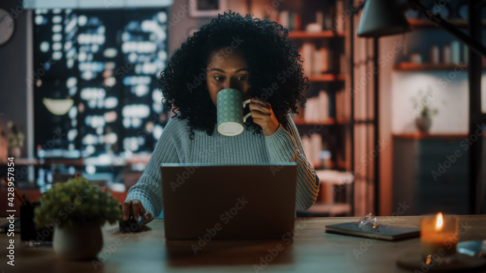 Poster beautiful authentic latina female sitting at a desk in a cozy dark living room in the evening and us