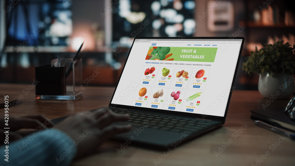 Fototapete close up on hands of a female using laptop computer with groceries delivery web page to order fresh 
