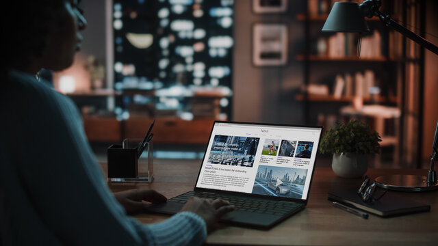 Close Up Shot of a Female Specialist Working on Laptop, Reading Latest News for Market Analysis. Freelancer Female at Home Living Room while Sitting at a Table and Using Computer.