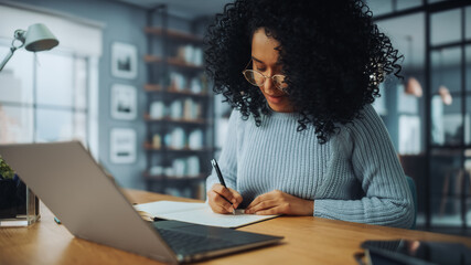 Beautiful Authentic Latina Female Sitting at a Desk in a Cozy Living Room and Following a Video...