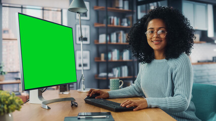 Latina Female Specialist Working on Desktop Computer with Green Screen Mock Up Display at Home...