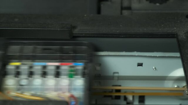 Continuous ink supply system is working in printer moving inside, closeup view. Printing new inkjet printer for launch, CISS. Small printer for use and printing at home, filled with only black paint.