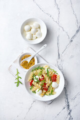 Pasta with cherry tomatoes, soft cheese, mustard sauce and arugula leaves