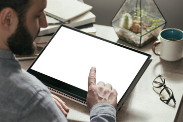 A man clicks on the touchscreen of a digital tablet. White screen for your design. Free space for text.