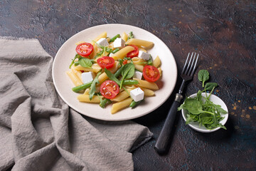 Penne pasta with cherry tomatoes, soft cheese, green beans, spinach and arugula leaves