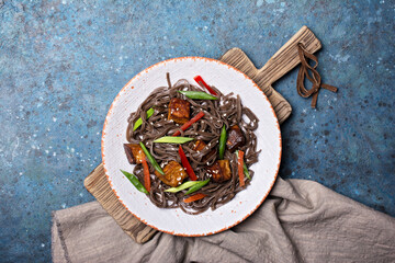 A dish of Asian cuisine. Soba noodles with red bell pepper, green onions and fried tofu cheese