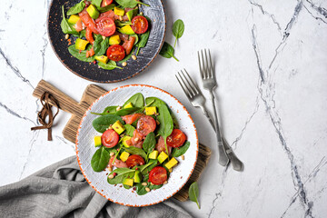 Healthy salad with fresh baby spinach, cherry tomatoes, avocado and salmon fish