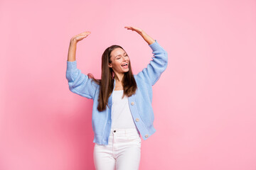 Fototapeta na wymiar Photo of cute pretty young woman dressed knitted cardigan smiling dancing rising hands arms isolated pink color background