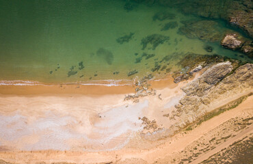 Aerial photography of sunny beach and rocks from above with clear water