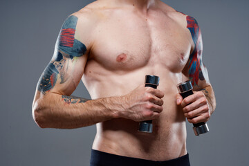 Naklejka premium male athlete with a tattoo on his arm naked torso inflated muscles dumbbells fitness