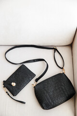 a few black leather women's bags are lying on a white sofa