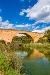 Fototapeta na wymiar Antique one arch stone bridge over a river the Hoces del Rio Cabriel Natural Park between Valencia and Cuenca in Spain. Protected Area. 
