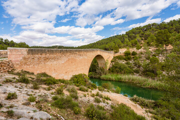 Antique one arch stone bridge over a river the Hoces del Rio Cabriel Natural Park between Valencia and Cuenca in Spain. Protected Area. 