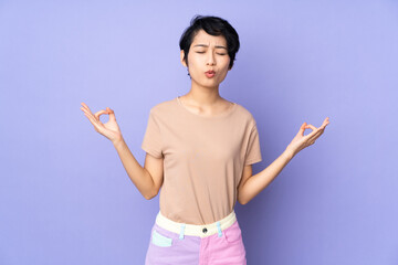 Young Vietnamese woman with short hair over isolated purple background in zen pose