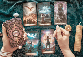 tarot cards in the hands of a young woman, candles and runes on a blue velvet background, concept...