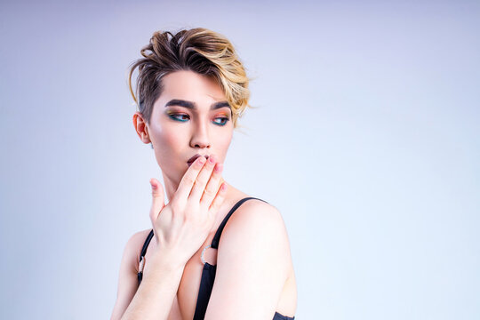 blond man with make up on face posing in studio on white background