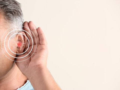 Mature man with hearing problem on light background, closeup. Space for text