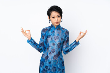 Young Vietnamese woman with short hair wearing a traditional dress over isolated white background in zen pose