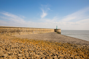 Large pier made of stones next to a paved beach on the North Sea. Lots of stones on a beach in a marine town in Germany. North Sea in Wilhelmshaven. 