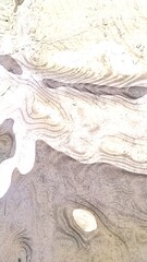 Light brown abstraction from different spots. On a light white-yellow background, there are several spots of brown and white colors around and inside of which there are gray-black lines like streaks.