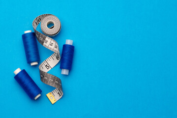 Thread spools and measuring tape on blue background
