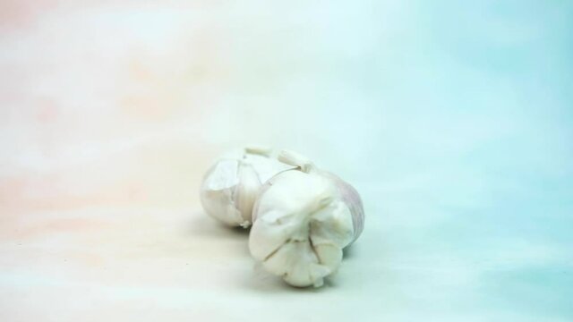 Slow motion and panning of fresh garlic rolling rolling into. Close-up.