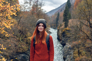 pretty woman hiker in autumn clothes in the mountains near the river nature