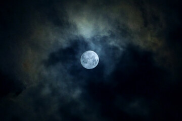 Naklejka na ściany i meble 薄曇りの夜空でわずかな雲の隙間で輝く満月のかすみ月