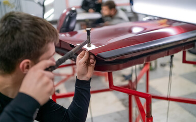 Close shot of dent removing without paint, young professional worker makes accurate blow rubber...