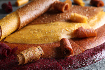 Delicious fruit leather rolls on grey table, closeup