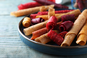Delicious fruit leather rolls on blue wooden table, closeup