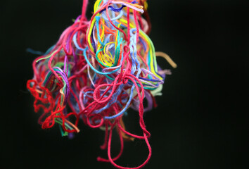 Obraz na płótnie Canvas Ball of multicolored tangled threads for needlework on black background