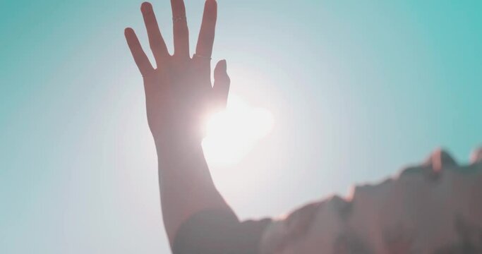 Waving hand to glare of sun flare in afternoon time, urban street. Woman's hand on balcony, sunbeams an gesture.