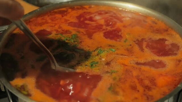 Real Ukrainian borscht is cooked in a saucepan. The chef prepares Ukrainian borscht. The chef mixes boiling Ukrainian borsch with a spoon.