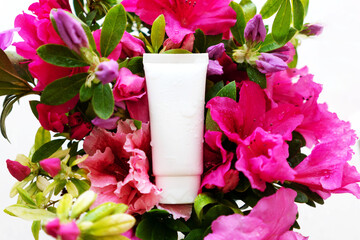white cosmetic tube for face cream, body wash, face mask or body lotion on a background strewn with flowers. The concept of a flavored cosmetic product