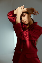 pretty woman holding hand near face fashion posing red jacket