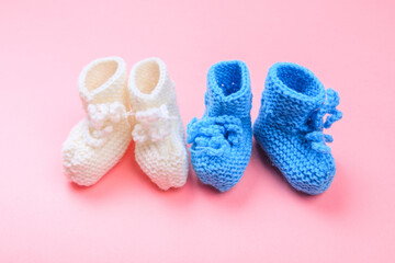 knitted baby booties on pastel pink background.