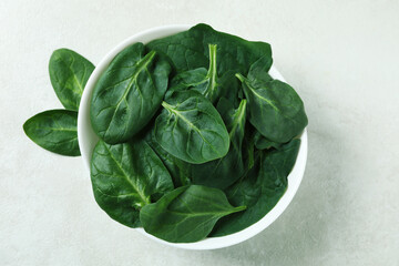 Bowl of spinach on white textured background