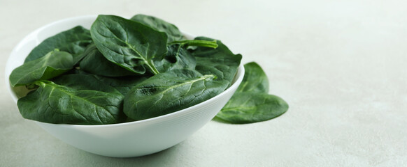 Bowl of spinach on white textured background