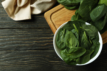 Bowl of spinach on cutting board on wooden table