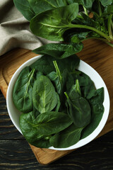 Bowl of spinach on cutting board on wooden table