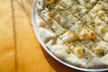 large freshly baked pizza with spices sprinkled with cheese in bright sunlight
