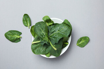 Bowl of spinach leaves on light gray background