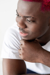 Fototapeta na wymiar Happy black man. Positive mind. Hipster style. Studio shooting. Handsome smiling african guy with pink hair white t-shirt leaning hand isolated light.