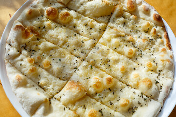 large freshly baked pizza with spices sprinkled with cheese in bright sunlight